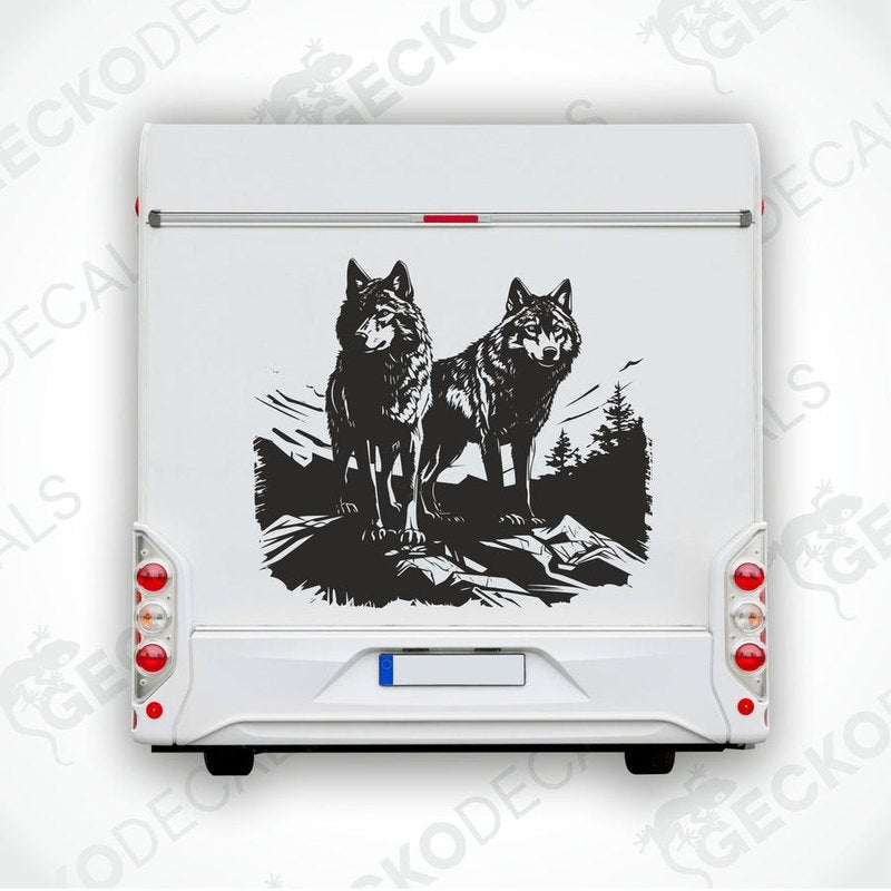 A black die cut decal of two wolves on the edge of a cliff, intended for use on vehicles or other surfaces.