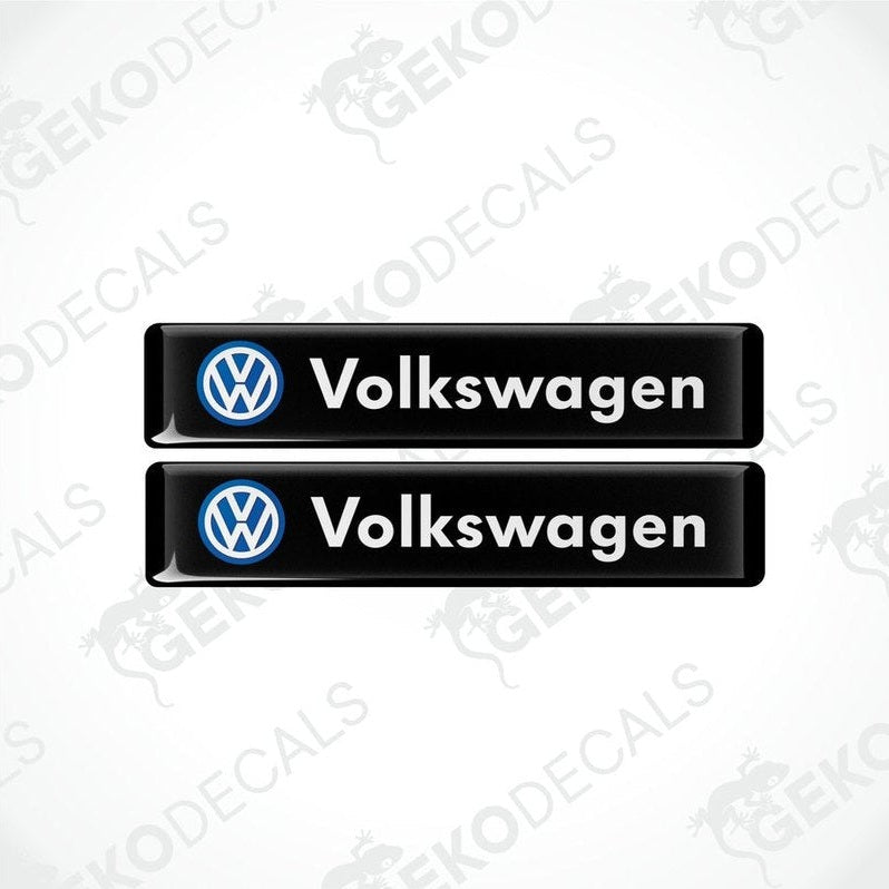 Two black vinyl stickers with the word 'VOLKSWAGEN' written in white and a blue logo of the same name.