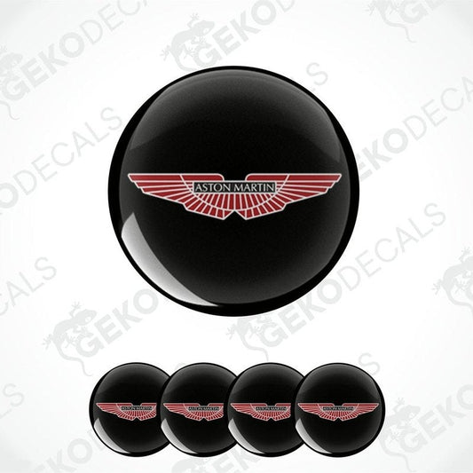 A set of vinyl decals with the Aston Martin logo applied on black circular surfaces, likely for vehicle wheels.
