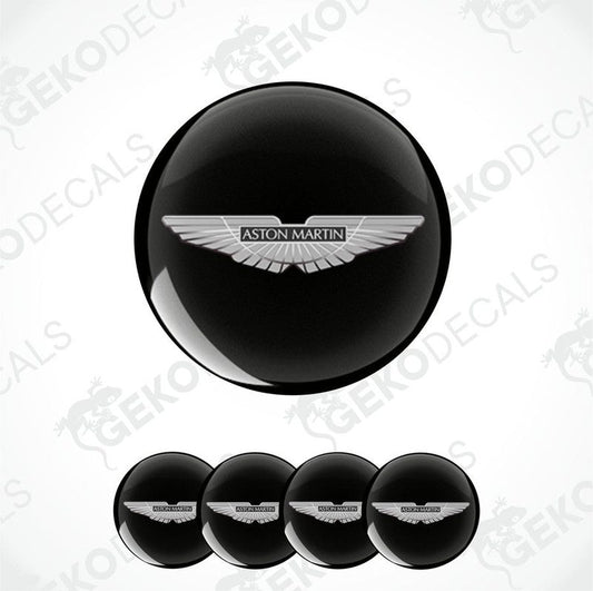 A set of vinyl decals with the Aston Martin logo applied on black circular surfaces, likely for vehicle wheels.