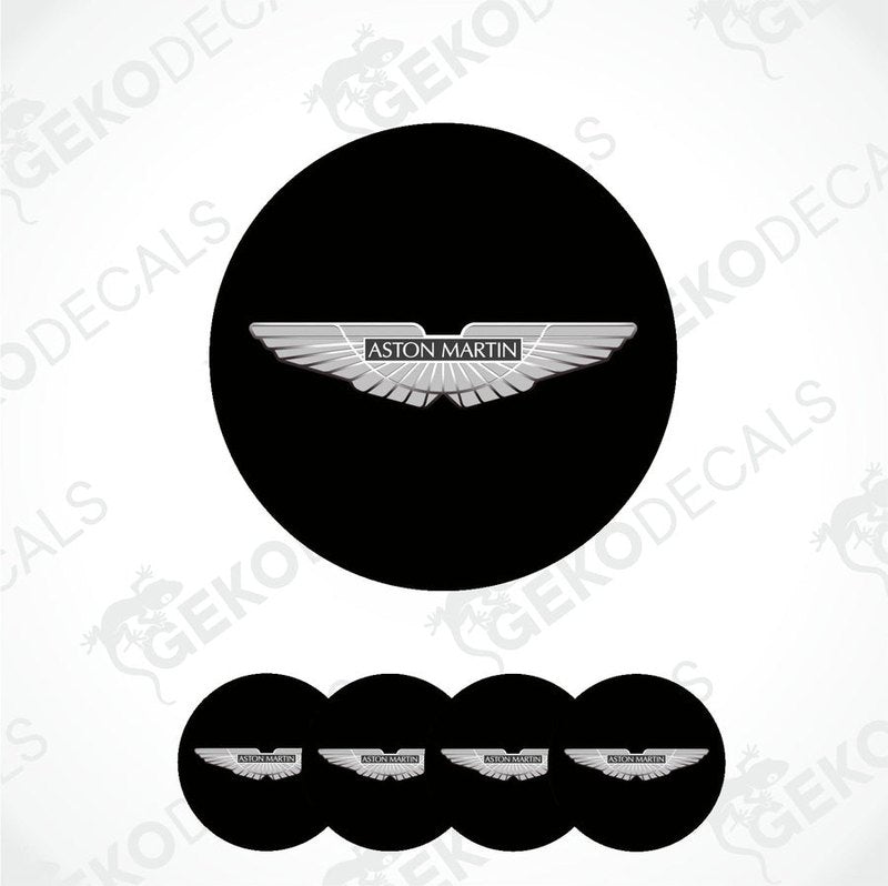 A set of vinyl decals with the Aston Martin logo applied on black circular surfaces, likely for vehicle wheels.