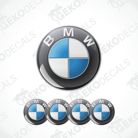 A set of four BMW emblem stickers, with one large emblem in the center and three smaller ones around it, all in black, blue, and white colors.