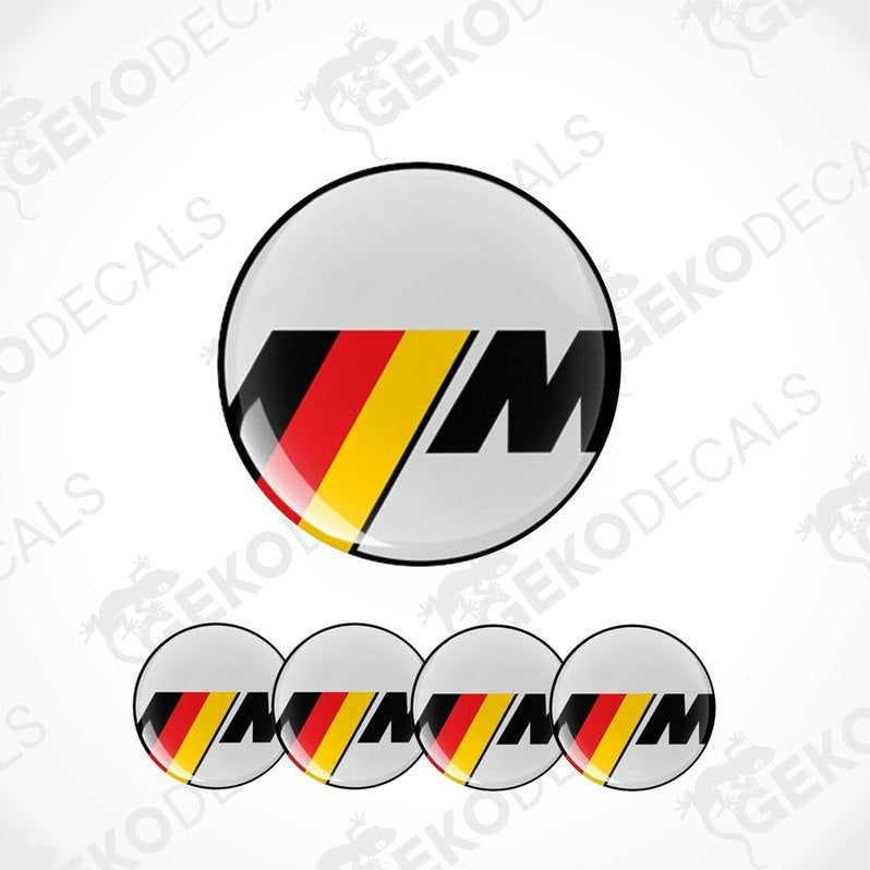 A set of four round vinyl stickers with a geometric pattern in red, black, and yellow colors, featuring the letter 'M' in the center.