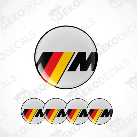 A set of four round vinyl stickers with a geometric pattern in red, black, and yellow colors, featuring the letter 'M' in the center.
