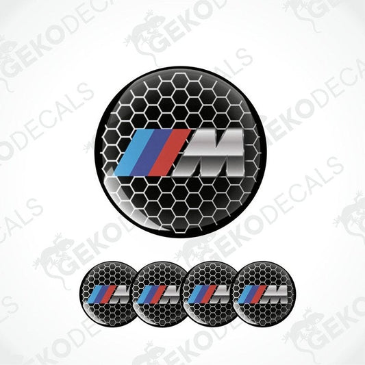 A set of four vinyl decals with a polyurethane coating, featuring the BMW M logo in black, red, blue, and silver colors on a hexagonal pattern background.