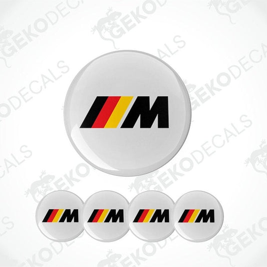 A set of four round car decals with a geometric pattern design, predominantly featuring the BMW M logo in red, yellow, and black colors.