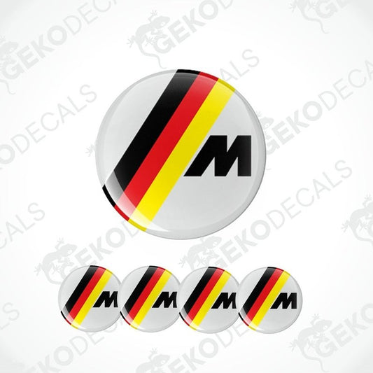 A set of four round vinyl stickers with a black, red, and yellow geometric pattern and the letter 'M' in the center, associated with BMW branding.