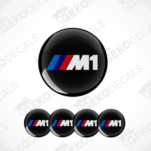 A set of four black vinyl stickers with the BMW M1 logo in white and red.