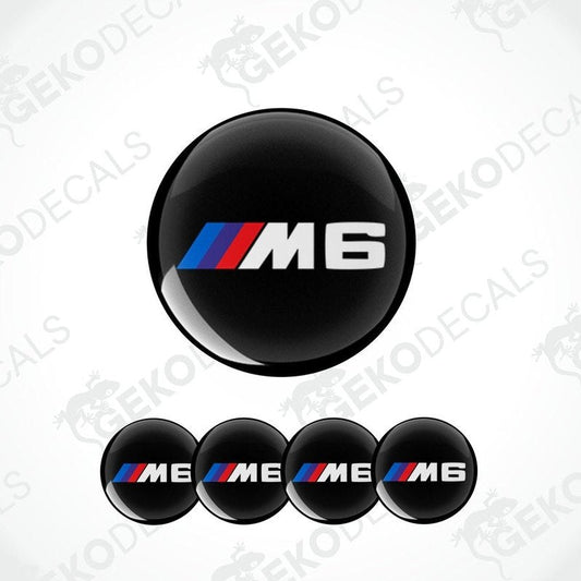A set of four black vinyl stickers with the BMW M6 logo, designed for use on car wheels.