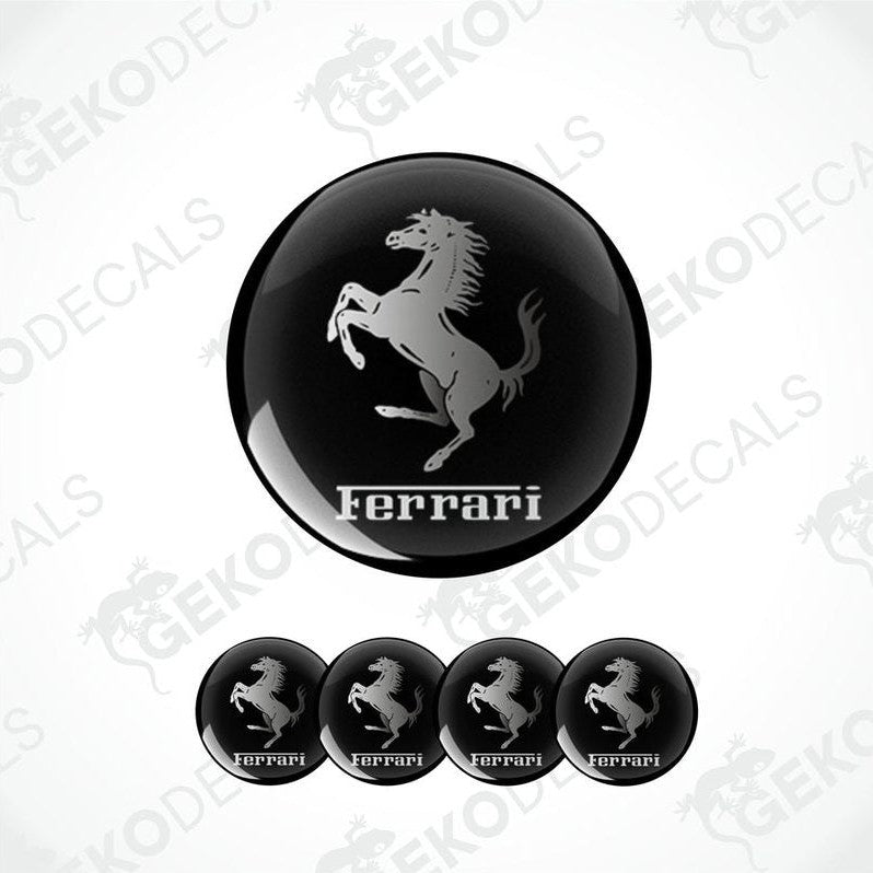 A set of four black vinyl stickers with a white Ferrari logo, designed for use on car wheels or caps.