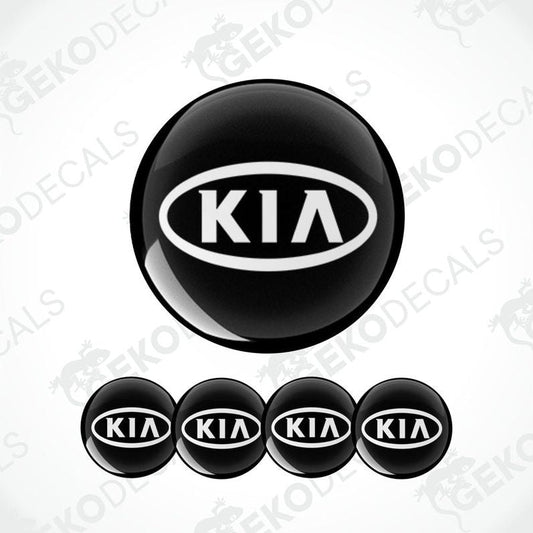 A set of four black vinyl stickers with the KIA brand logo on them.