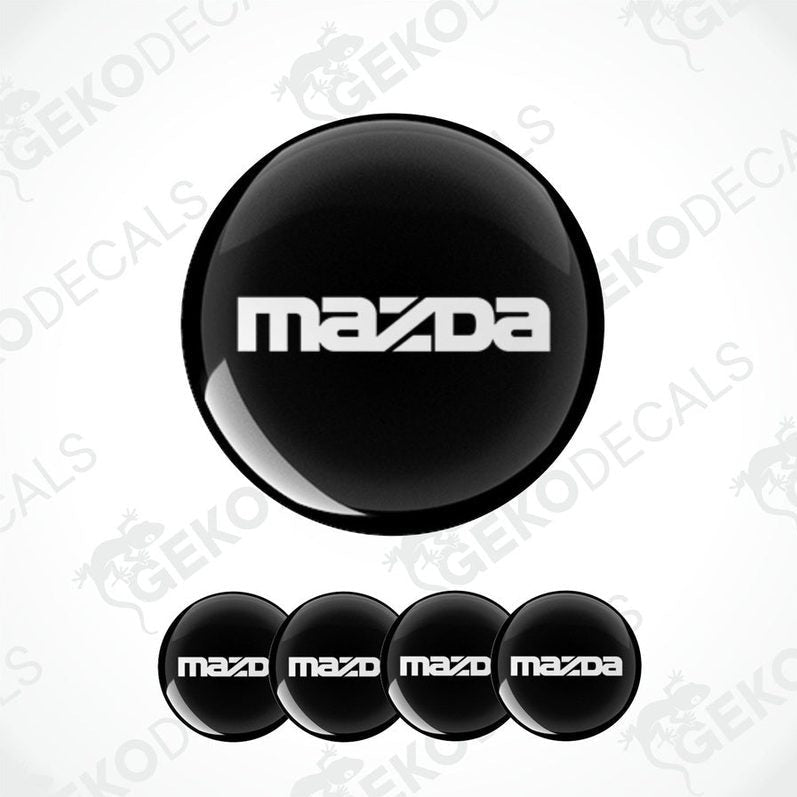 A set of four black vinyl stickers with the Mazda logo on them.