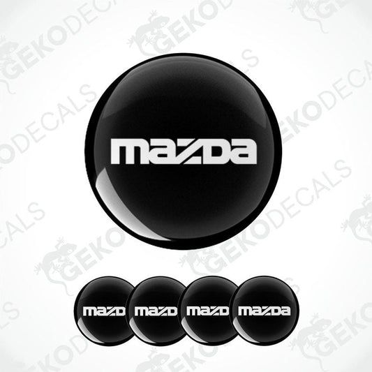 A set of four black vinyl stickers with the Mazda logo on them.