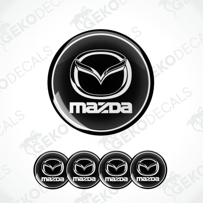 A set of black and white vinyl decals with the Mazda logo, including four different sizes shown against a white background.