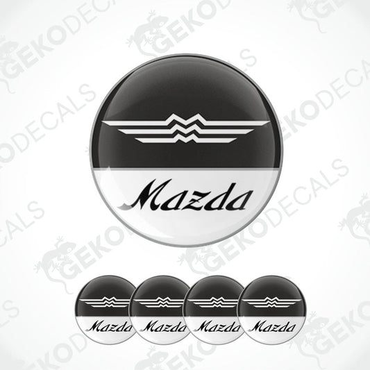 A set of four round MAZDA branded vinyl stickers with a black, white, and gray color scheme on a white background.