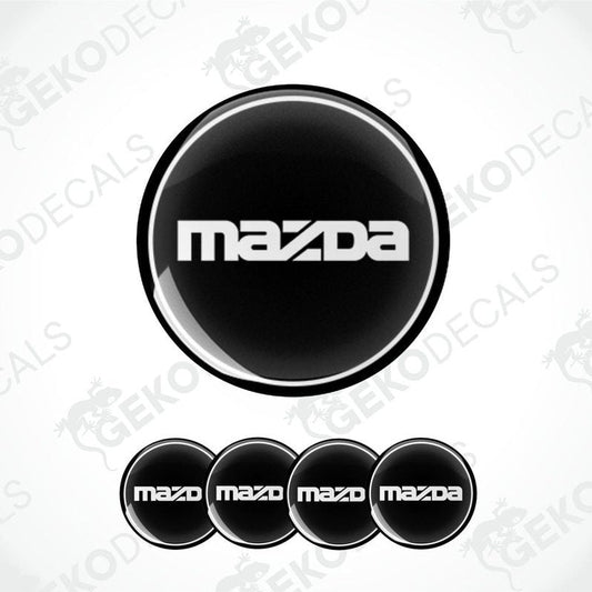 A set of four black vinyl stickers with the Mazda logo on them.