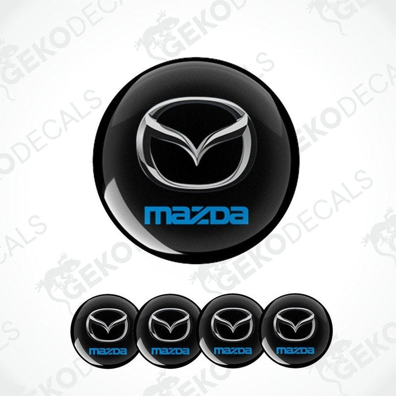 A set of black round car decals with  silver and blue Mazda logo in the center. 