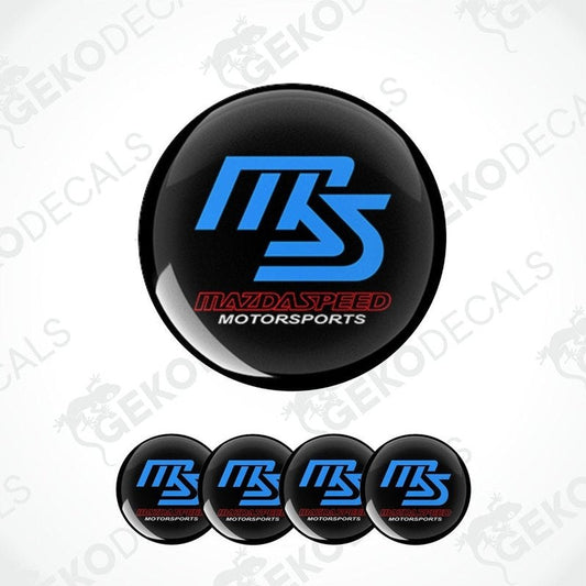 A set of four black, blue, and red vinyl decals with the text 'MAZDASPEED' and 'MOTORSPORTS', designed for use as car wheel caps or stickers.