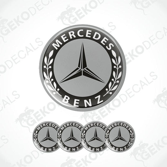 A set of four black and grey Mercedes-Benz wheel decals with a star logo in the center.