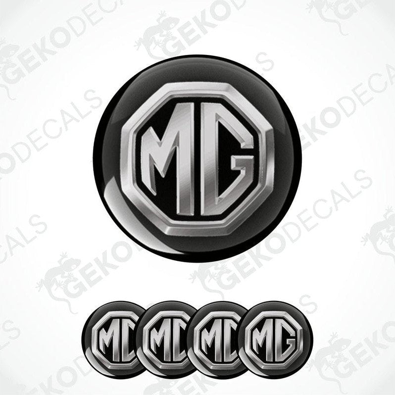 A set of four black and silver vinyl decals with the MG logo, designed for use as car wheel caps.