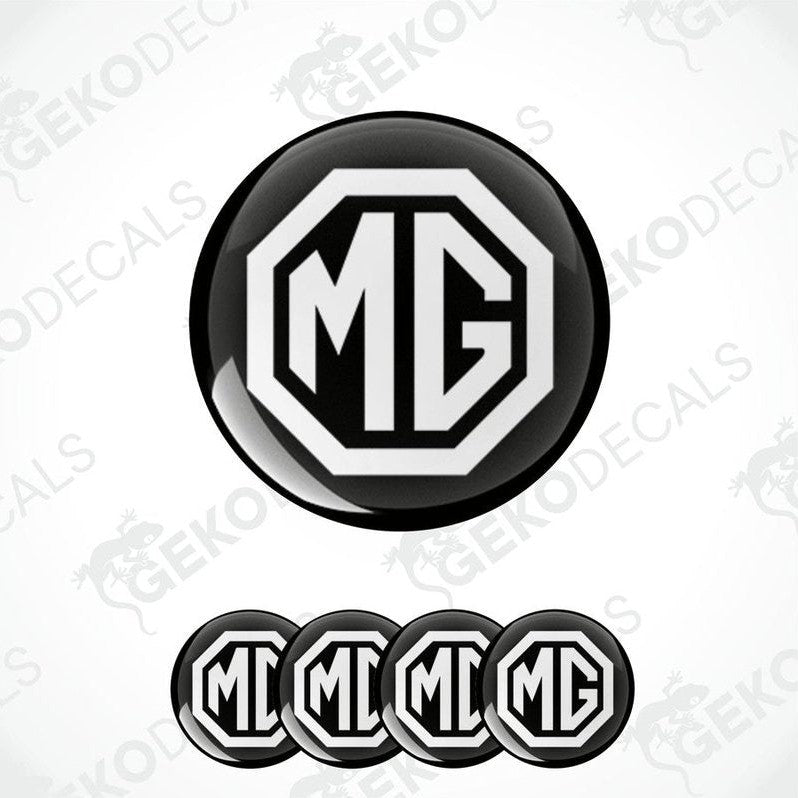A set of four black and white vinyl decals with the MG logo, designed for use as car wheel caps or domed stickers.