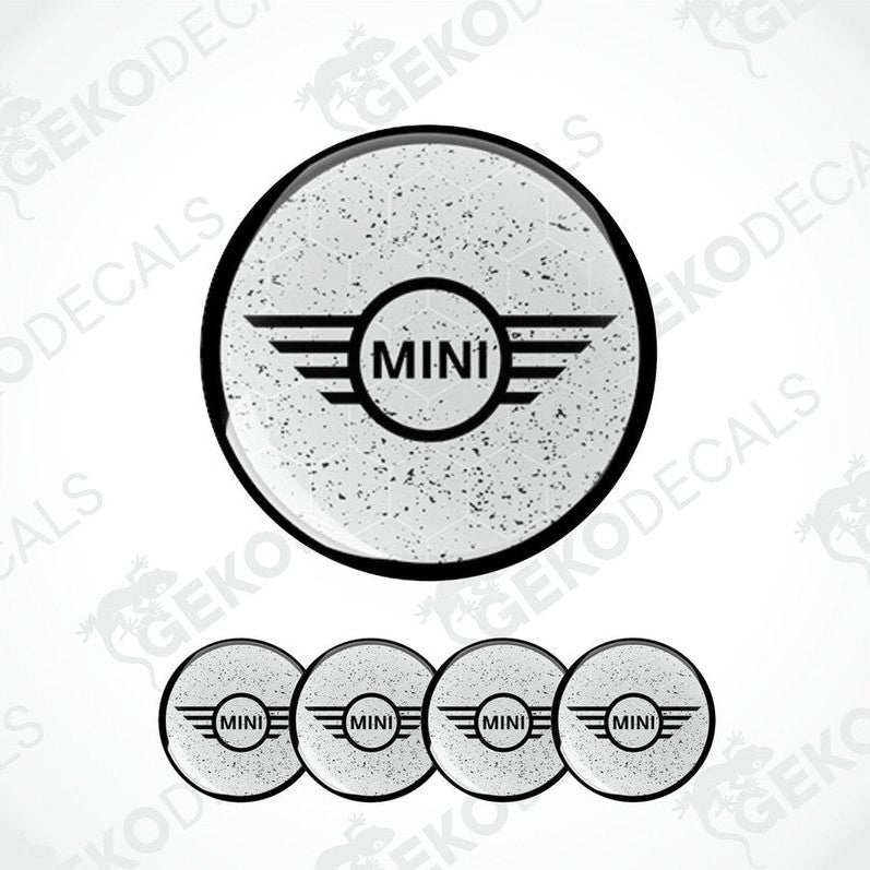 A set of four gray vinyl stickers with the word 'MINI' in the center, designed for use on car wheels or other surfaces.