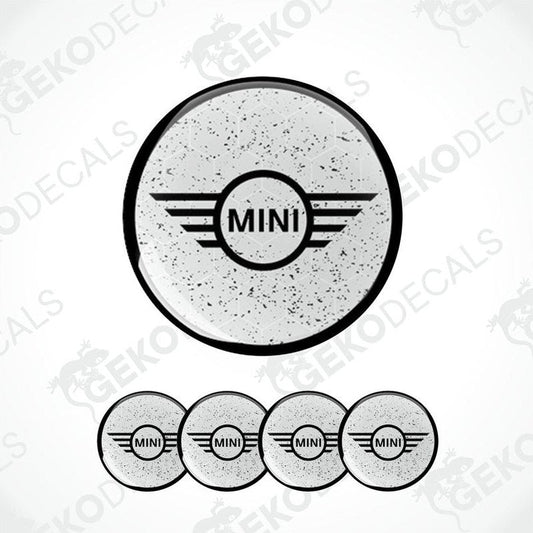 A set of four gray vinyl stickers with the word 'MINI' in the center, designed for use on car wheels or other surfaces.