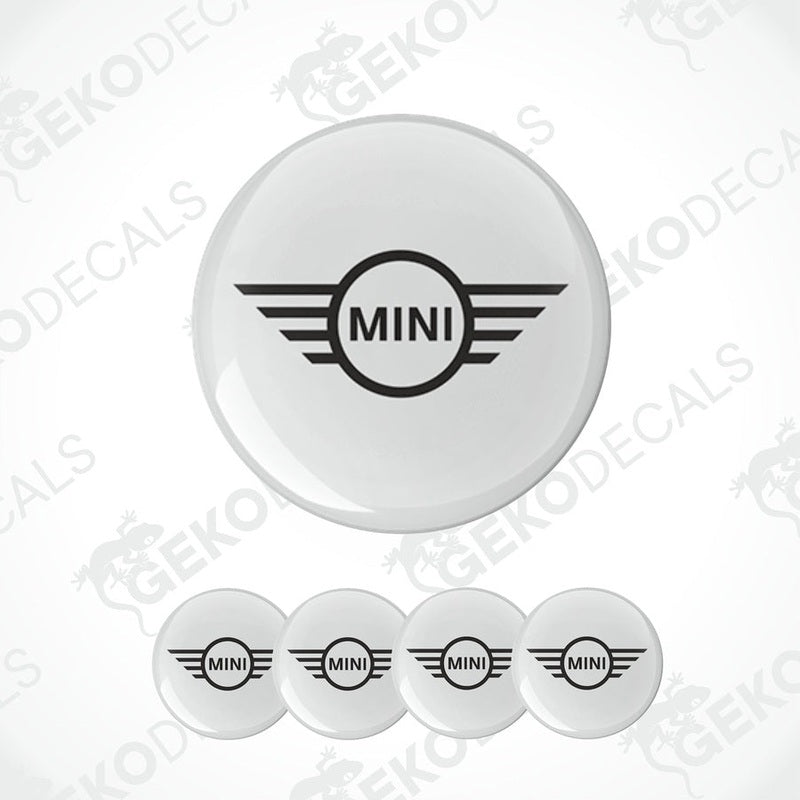 A set of four white vinyl stickers with the MINI Cooper brand logo in the center, designed for use on car wheels or other surfaces.