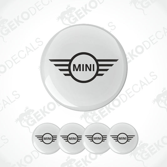 A set of four white vinyl stickers with the MINI Cooper brand logo in the center, designed for use on car wheels or other surfaces.