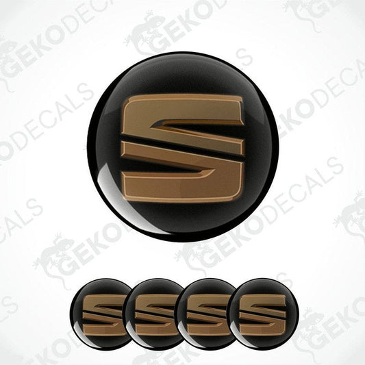 A set of four black and chrome brown vinyl stickers with the letter 'SEAT' in the center, designed for use as car decals.