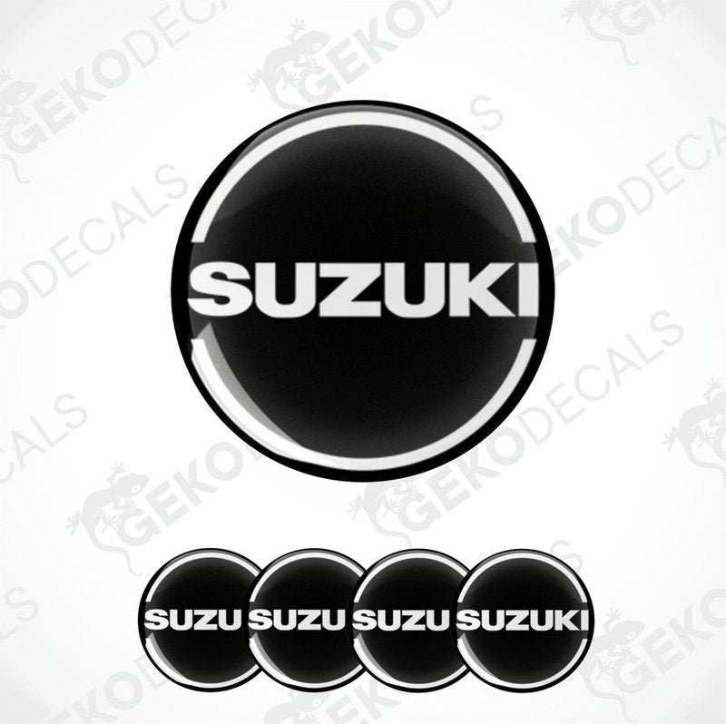 A set of four black and white vinyl stickers with the word 'SUZUKI' in bold letters, designed for use on car decals or wheel caps.