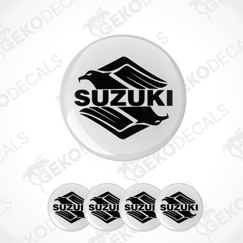 A set of four white vinyl stickers with the SUZUKI brand logo printed on them.