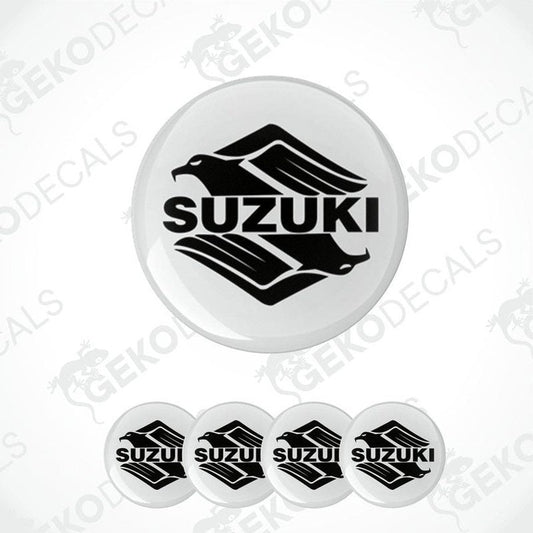 A set of four white vinyl stickers with the SUZUKI brand logo printed on them.