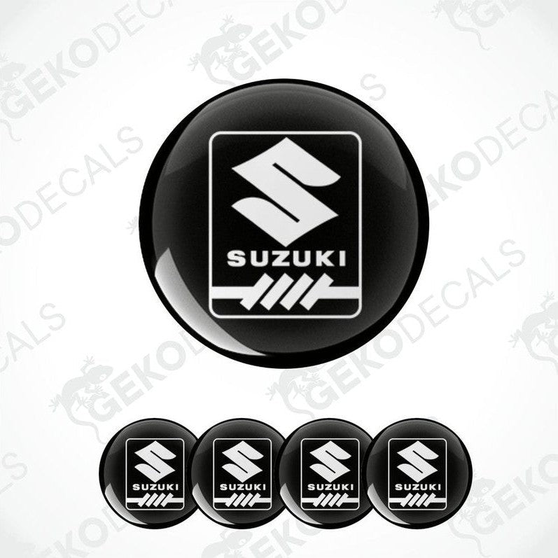 A set of four black round decals with the white Suzuki logo in the center.