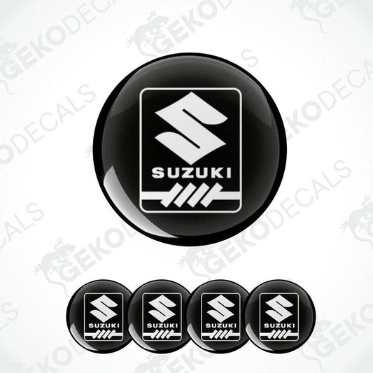 A set of four black round decals with the white Suzuki logo in the center.