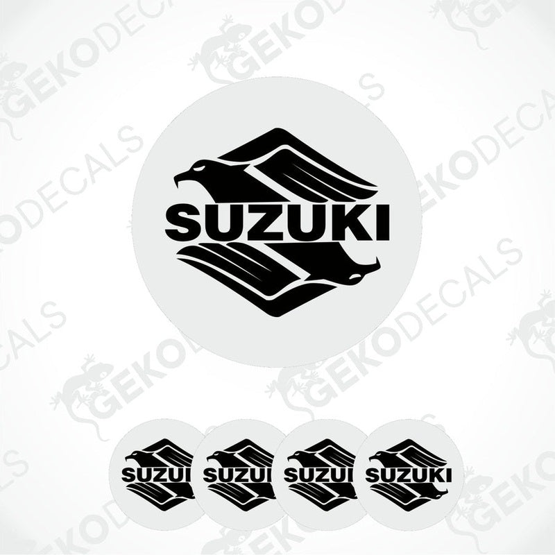 A set of four white vinyl stickers with the SUZUKI brand logo printed on them.