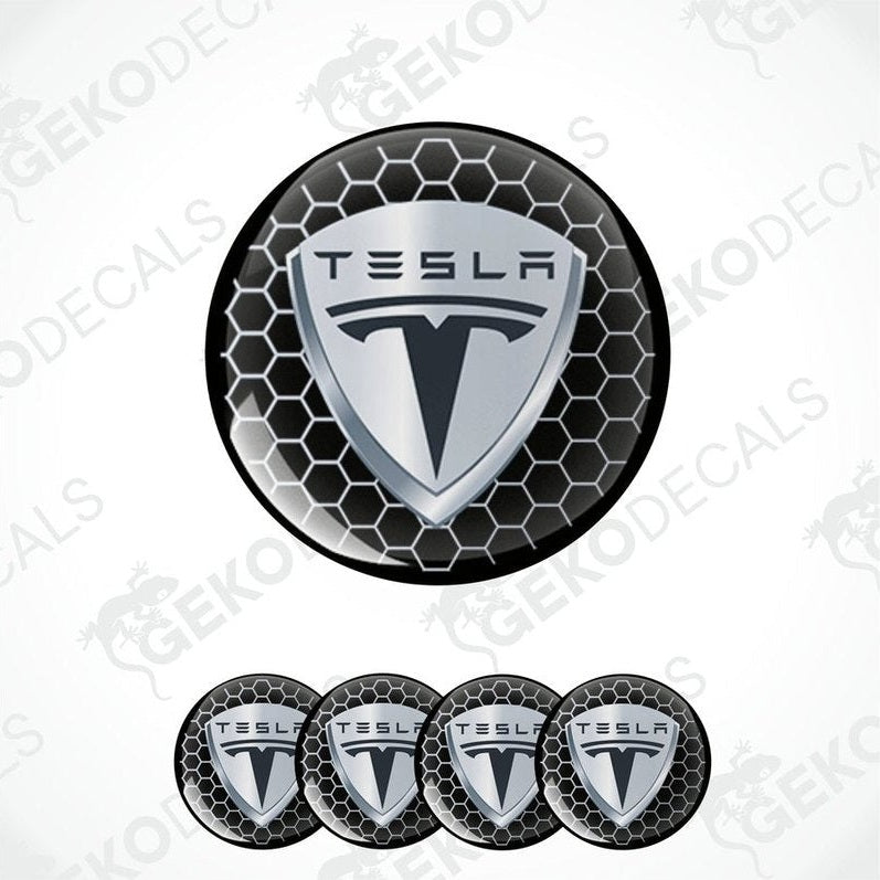 A set of four round Tesla branded vinyl stickers with a geometric pattern in black, white, and gray colors.