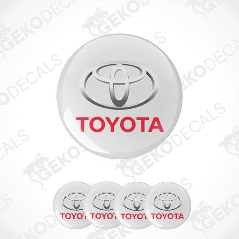 A set of four white vinyl decals with the TOYOTA logo and the word 'TOYOTA' written in red below the logo.