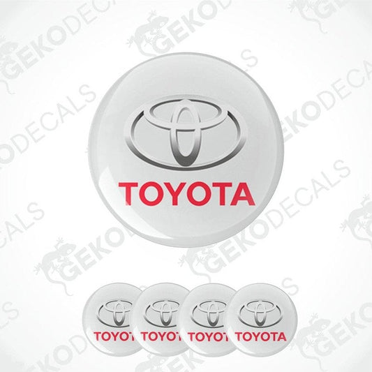 A set of four white vinyl decals with the TOYOTA logo and the word 'TOYOTA' written in red below the logo.