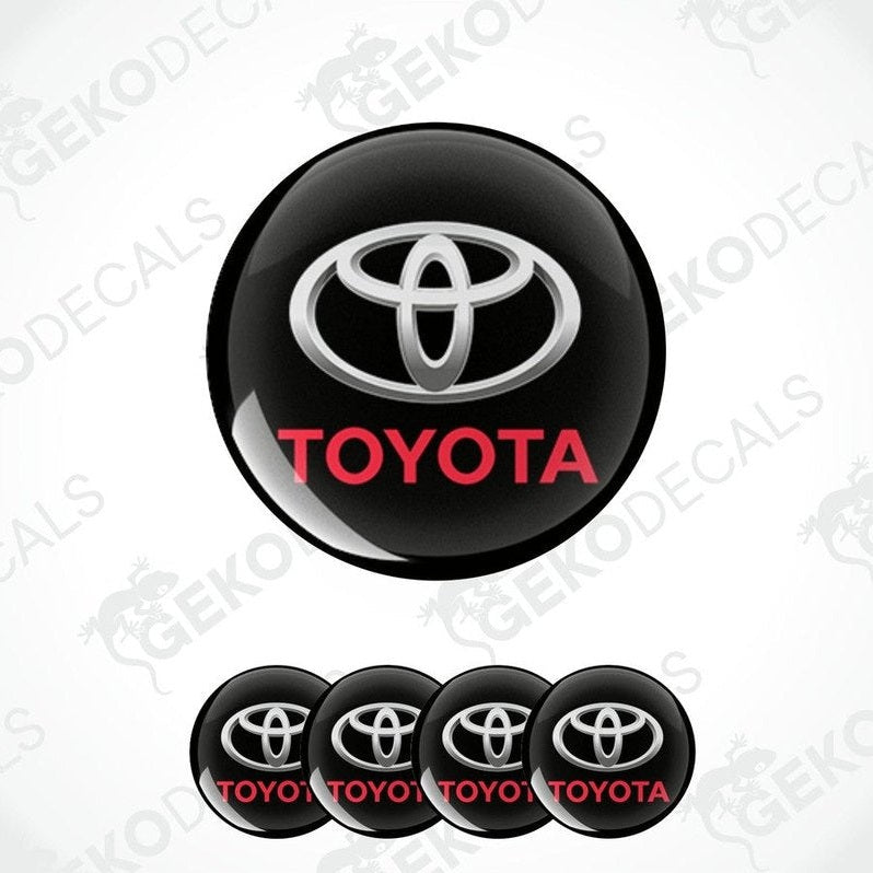 A set of black, white, and red Toyota wheel decals. The main decal is circular with the Toyota logo in white and red on a black background.