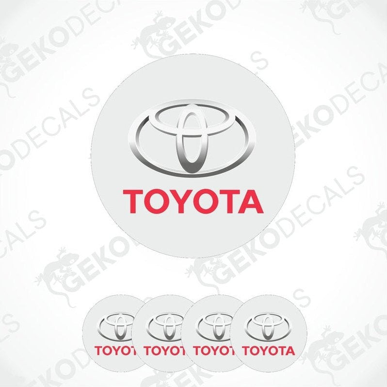 A set of four white vinyl decals with the TOYOTA logo and the word 'TOYOTA' written in red below the logo.