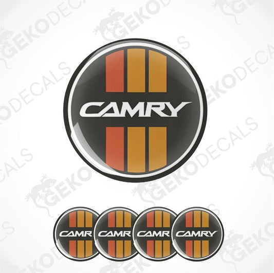 A set of four black, red, and orange vinyl stickers with the word 'CAMRY' in the center, designed for use on car wheel caps.