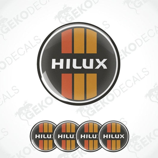 A set of four red, orange, and black vinyl stickers with the word 'HILUX' on them, arranged in a circular pattern with a white background.