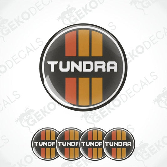 A set of four orange, black, and white vinyl stickers with the word 'TUNDRA' printed on them.